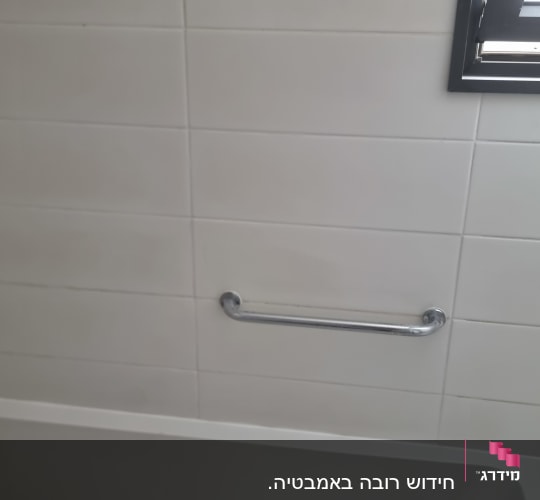 ידית אחיזה מתכתית על קיר אריחים בחדר אמבטיה
